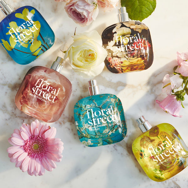 Collection of Floral Street bestselling perfume bottles on a marble surface with flowers.